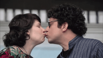 A Man And A Woman Are Kissing And The Man Is Wearing Glasses GIF