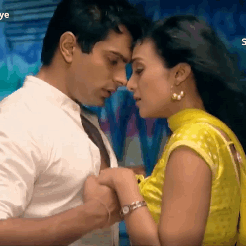 A Man And A Woman Are Kissing And The Woman Is Wearing A Yellow Blouse . GIF