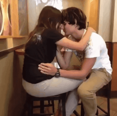 A Man And A Woman Are Kissing At A Table GIF