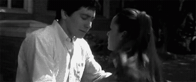 A Man And A Woman Are Kissing Each Other In A Black And White Photo . GIF