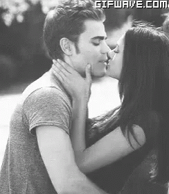 A Man And A Woman Are Kissing Each Other In A Black And White Photo . GIF