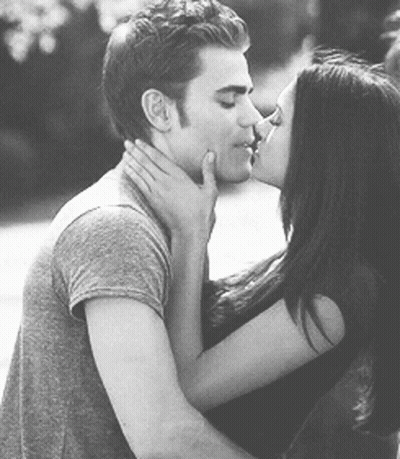 A Man And A Woman Are Kissing Each Other In A Black And White Photo . GIF