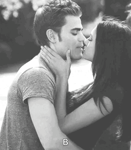 A Man And A Woman Are Kissing Each Other In A Black And White Photo . GIF