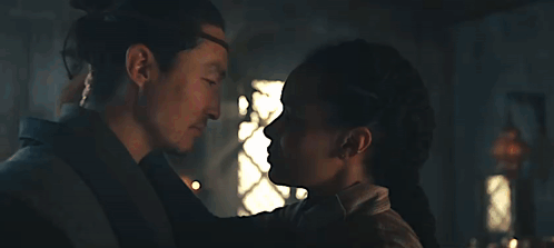 A Man And A Woman Are Kissing Each Other In A Dark Room . GIF