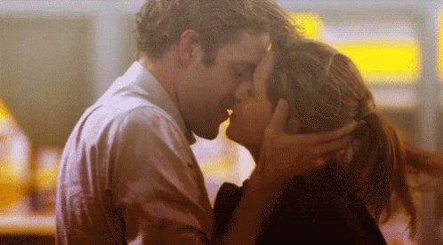 A Man And A Woman Are Kissing Each Other In A Room . GIF
