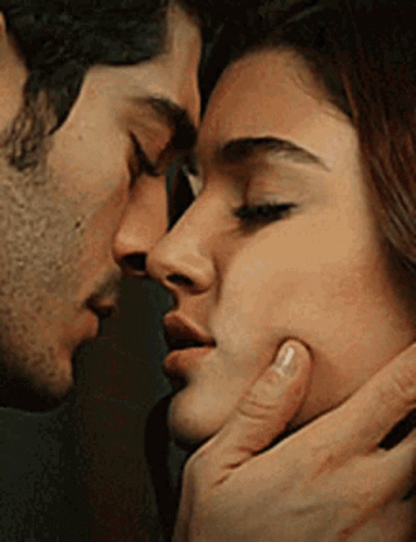 A Man And A Woman Are Kissing Each Other On The Cheek . GIF