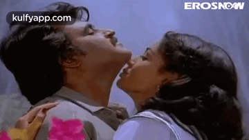 A Man And A Woman Are Kissing Each Other On The Cheek . GIF