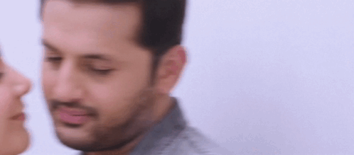 A Man And A Woman Are Kissing Each Other On The Cheek . GIF