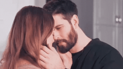 A Man And A Woman Are Kissing Each Other . The Man Has A Beard And The Woman Has Long Hair . GIF