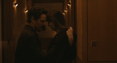 A Man And A Woman Are Kissing In A Dark Hallway GIF