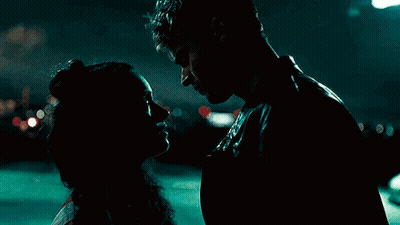 A Man And A Woman Are Kissing In A Dark Room At Night . GIF