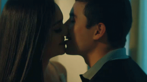 A Man And A Woman Are Kissing In A Dark Room GIF