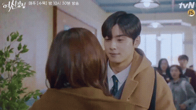 A Man And A Woman Are Kissing In A Hallway . GIF