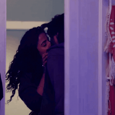 A Man And A Woman Are Kissing In A Room With Purple Lights GIF
