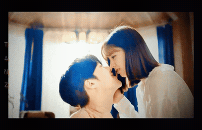 A Man And A Woman Are Kissing In A Room With The Letter T On The Bottom Right GIF