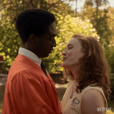 A Man And A Woman Are Kissing In Front Of A Netflix Ad GIF