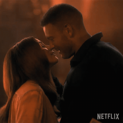 A Man And A Woman Are Kissing In Front Of A Netflix Logo GIF