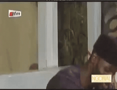 A Man And A Woman Are Kissing In Front Of A Window In A Room . GIF