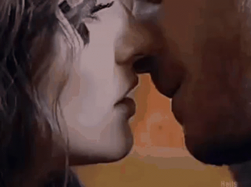 A Man And A Woman Are Kissing In Front Of A Yellow Background . GIF