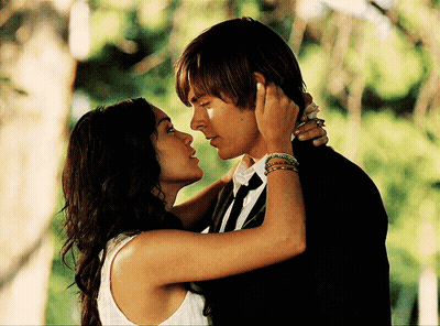 A Man And A Woman Are Kissing In Front Of Trees GIF