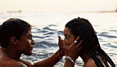 A Man And A Woman Are Kissing In The Ocean . GIF