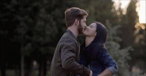 A Man And A Woman Are Kissing In The Park GIF