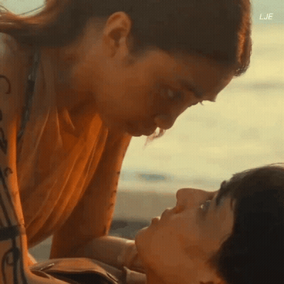 A Man And A Woman Are Kissing On The Beach With The Letters Lje On The Bottom GIF