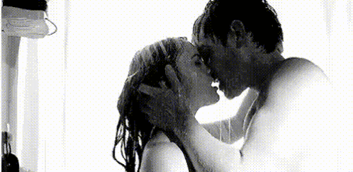 A Man And A Woman Are Kissing Under A Shower . GIF