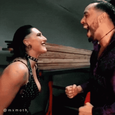 A Man And A Woman Are Laughing At Each Other While Standing Next To Each Other . GIF