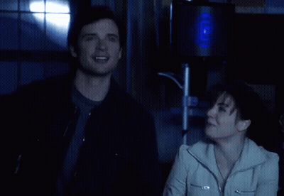 A Man And A Woman Are Laughing In Front Of A Speaker GIF