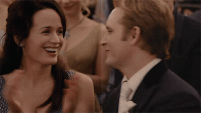 A Man And A Woman Are Laughing Together In A Crowd GIF