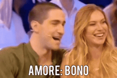 A Man And A Woman Are Laughing Together On A Stage And The Man Is Wearing A Microphone . GIF