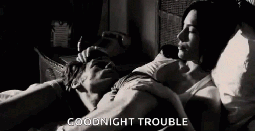 A Man And A Woman Are Laying In Bed And The Man Is Kissing The Woman On The Forehead . GIF
