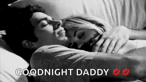 A Man And A Woman Are Laying In Bed Hugging And Kissing Each Other . GIF