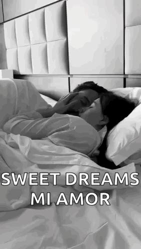 A Man And A Woman Are Laying In Bed Kissing . GIF
