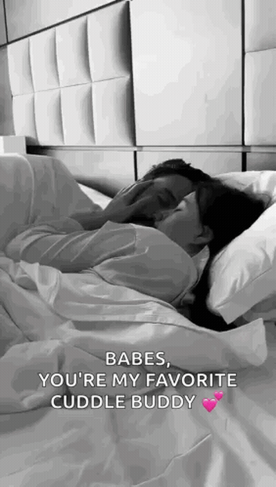 A Man And A Woman Are Laying In Bed Kissing . GIF