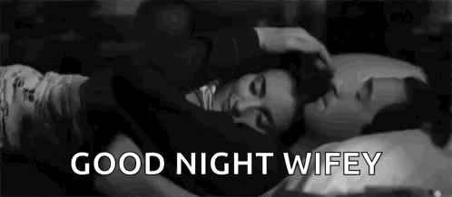 A Man And A Woman Are Laying In Bed Together And The Man Is Petting The Woman 'S Head . GIF