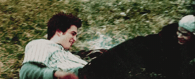 A Man And A Woman Are Laying In The Grass And Smiling At Each Other . GIF