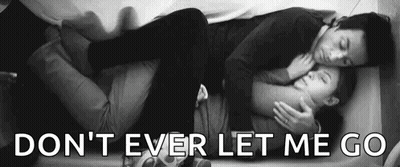A Man And A Woman Are Laying On A Bed And Hugging . GIF
