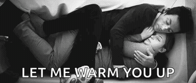 A Man And A Woman Are Laying On A Bed And Hugging . GIF
