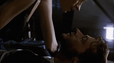 A Man And A Woman Are Laying On A Bed And Kissing GIF