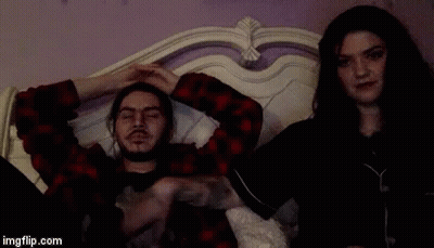 A Man And A Woman Are Laying On A Bed And The Man Has A Tattoo On His Arm GIF