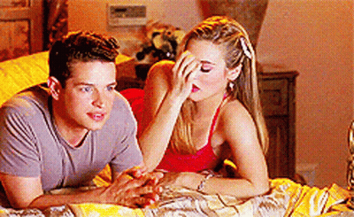 A Man And A Woman Are Laying On A Bed And The Woman Is Covering Her Face With Her Hand GIF