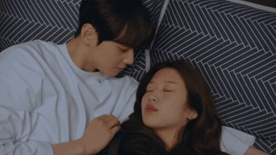 A Man And A Woman Are Laying On A Bed Together GIF