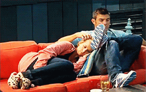 A Man And A Woman Are Laying On A Couch GIF
