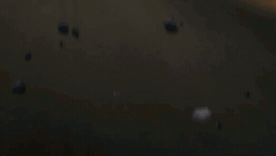 A Man And A Woman Are Laying On The Ground With A Fire Behind Them GIF
