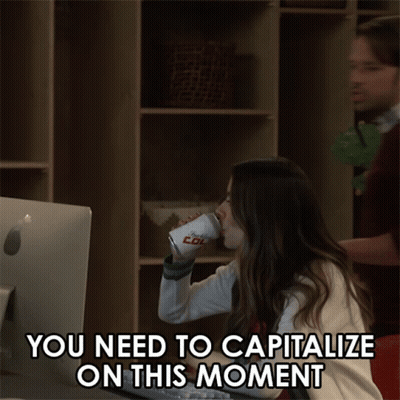 A Man And A Woman Are Looking At A Computer Screen With The Words You Need To Capitalize On This Moment GIF