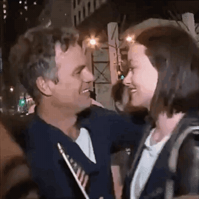 A Man And A Woman Are Looking At Each Other And Smiling . GIF