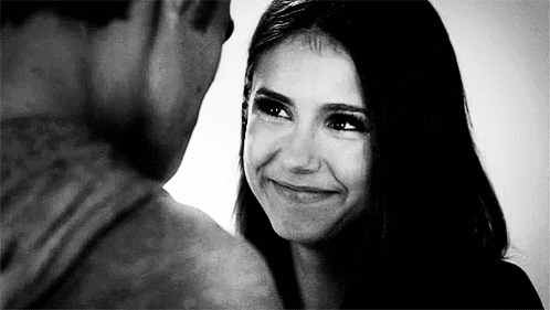 A Man And A Woman Are Looking At Each Other And Smiling . GIF