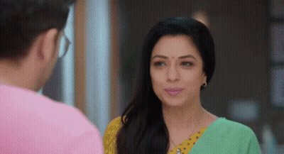A Man And A Woman Are Looking At Each Other And Smiling . The Woman Is Wearing A Green And Yellow Sari . GIF
